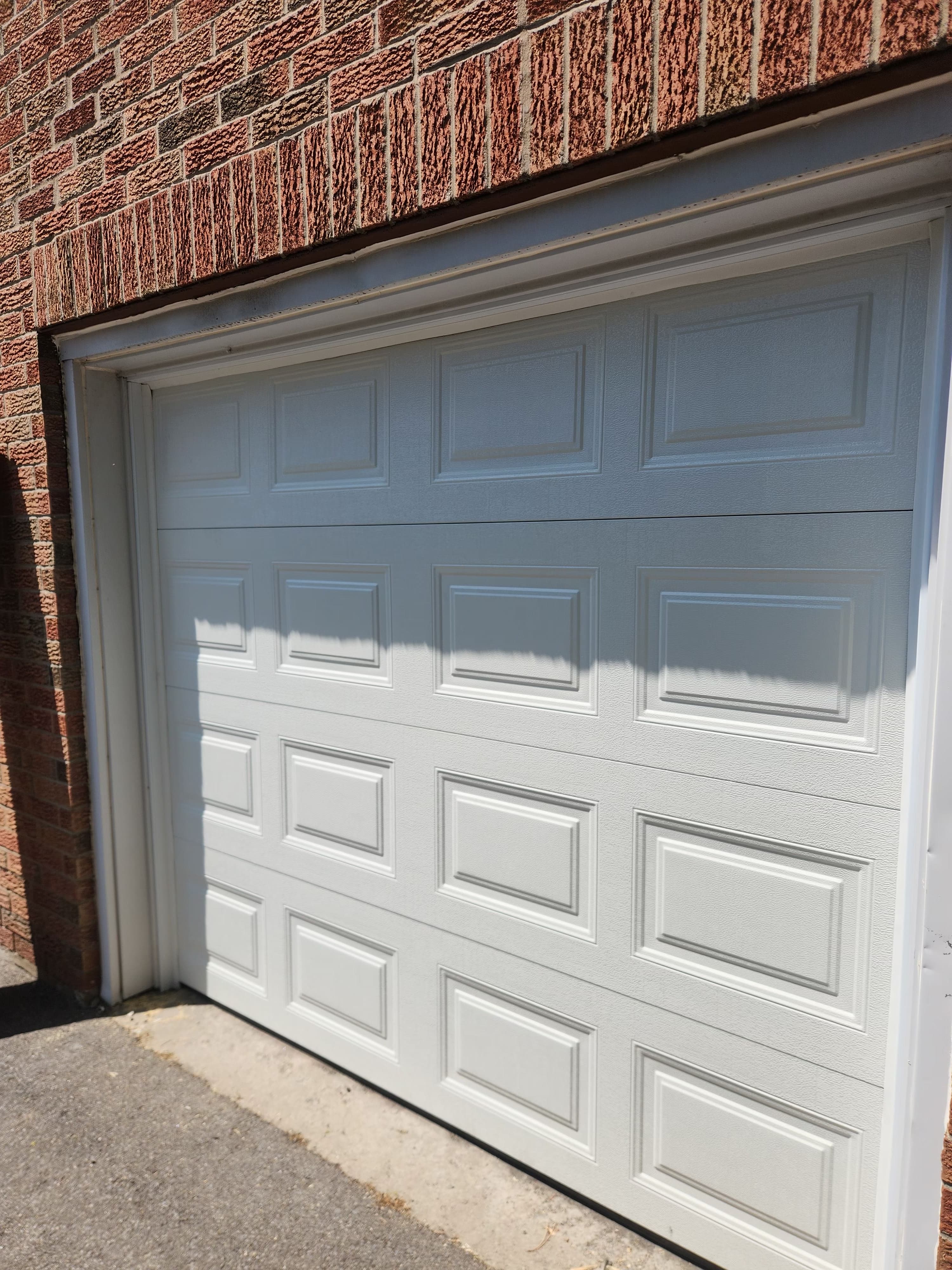 New white raised-panel garage door installation on brick home in Gloucester, Ottawa